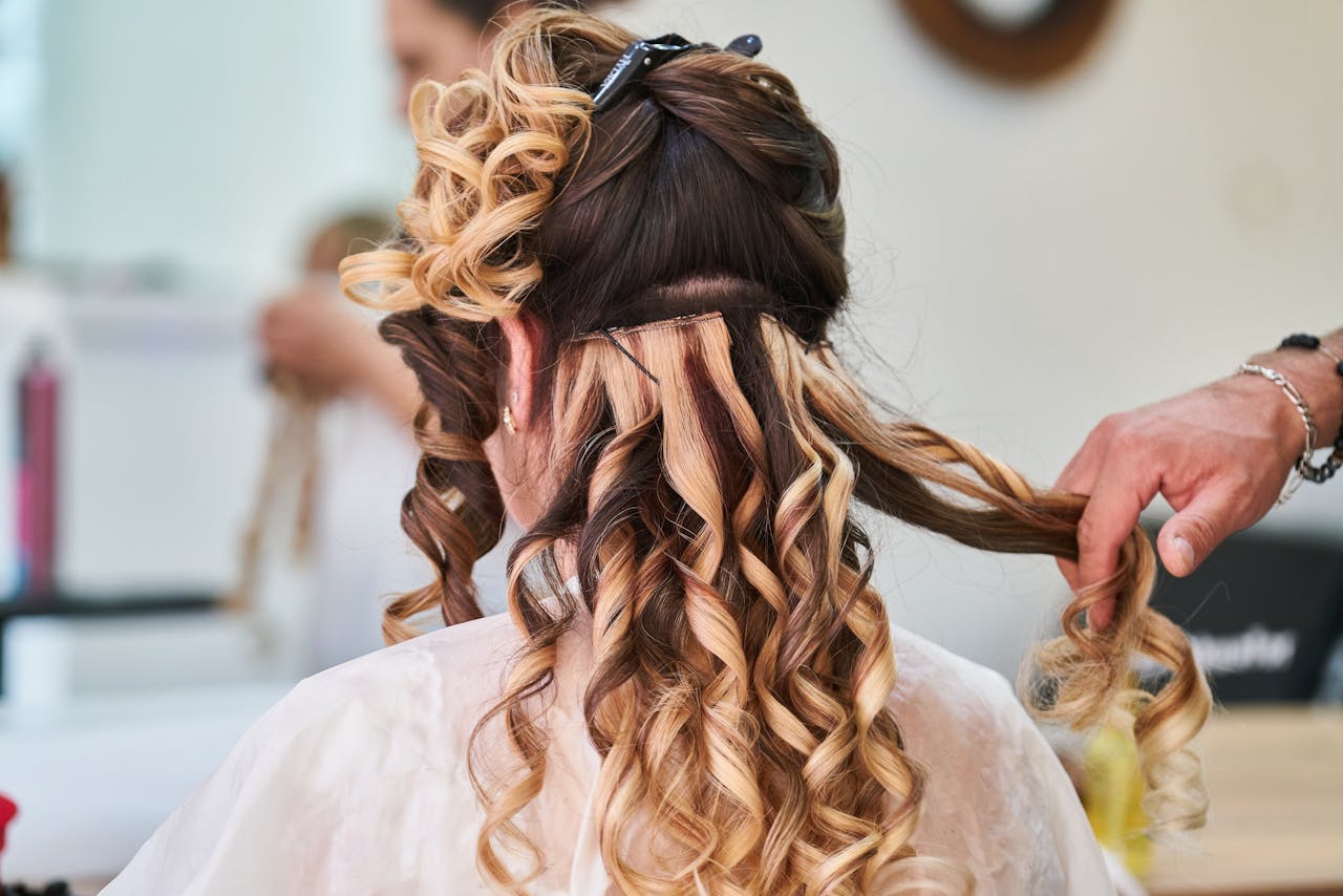 Close-up of hairstylist perfecting curls on a womans hair in a salon setting.